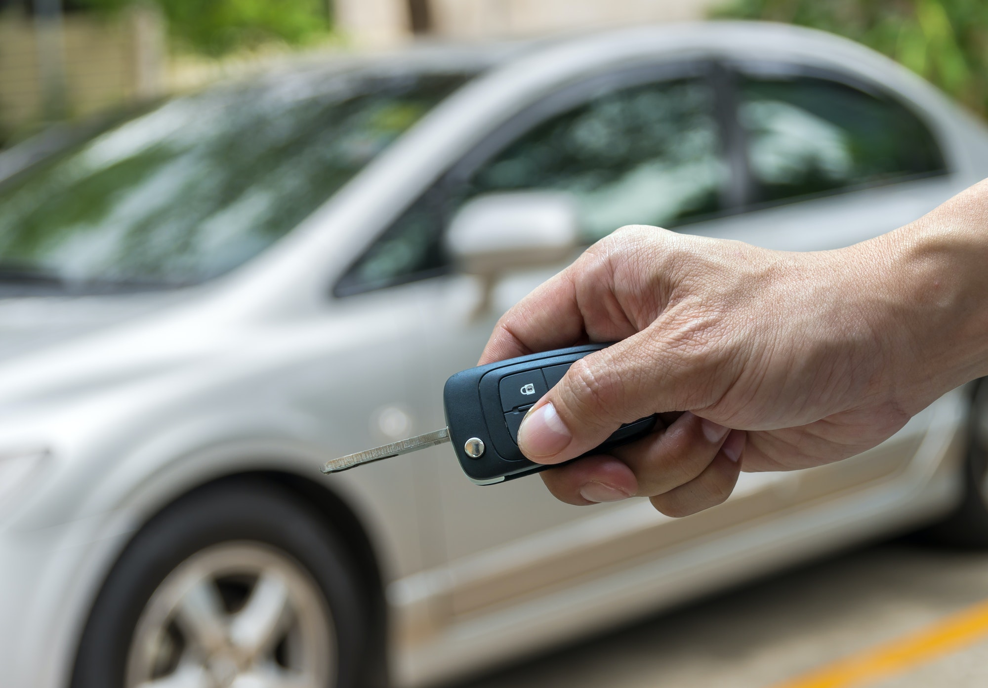 Hand holding the keys over photo blurred of used car for open the door car,